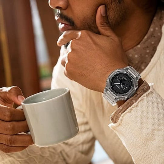 CASIO GA-2100SKE-7ADR G-Shock 200M 防水 防震 - 透明錶款佩戴於手腕，手持咖啡杯時尚生活照