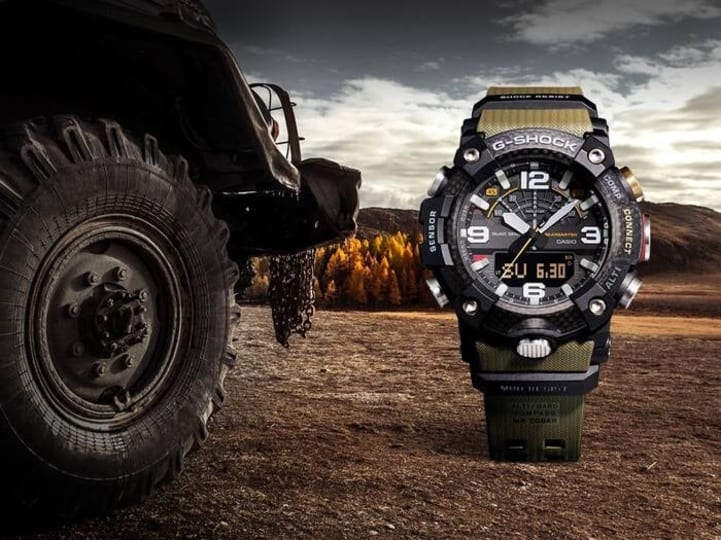 CASIO GG-B100-1A3DR G-Shock 樹脂錶帶 200米防水 - 手錶擺放於越野卡車輪胎旁，戶外時尚生活照